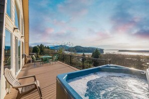 Un bain à remous sur une terrasse en bois, avec vue sur une plage et des montagnes.