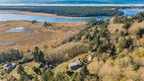 Un paysage côtier offrant une vue dégagée sur l’océan, une rivière et une zone boisée parsemée de maisons.
