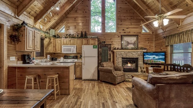 A log cabin interior with a kitchen, dining area, and fireplace.
