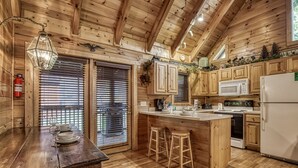 A wooden cabin-style kitchen with a central island, wooden cabinets, a microwave, and a refrigerator.