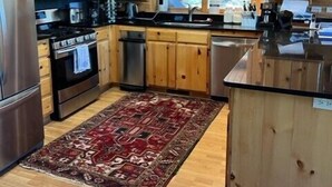 A cabin-style kitchen with wooden cabinets, stainless steel appliances, and a large window. - Hillside Rustic Retreat (Greer)