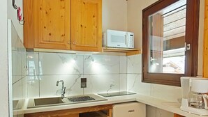 A compact kitchen with wooden cabinets, a built-in microwave, a sink, and a coffee maker. - Studio/Cabin/Mezz 5 pers with shuttle, 600m from center - Le Grand-Bornand (Le Grand-Bornand)