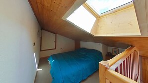 A small attic bedroom with a skylight, a bed, and a wooden staircase. - Studio/Cabin/Mezz 5 pers with shuttle, 600m from center - Le Grand-Bornand (Le Grand-Bornand)