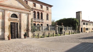 Un edificio histórico con un patio central, que cuenta con un gran arco de entrada y un balcón con barandilla.