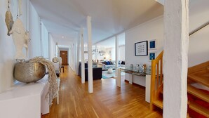 Un interior moderno con piso de madera, paredes blancas y una escalera.