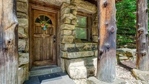 A rustic stone house with a wooden door, a small porch, and a window with a shutter. - ER69 - Rachel's Tree House - Great location. Close to all the action! (Pigeon Forge)