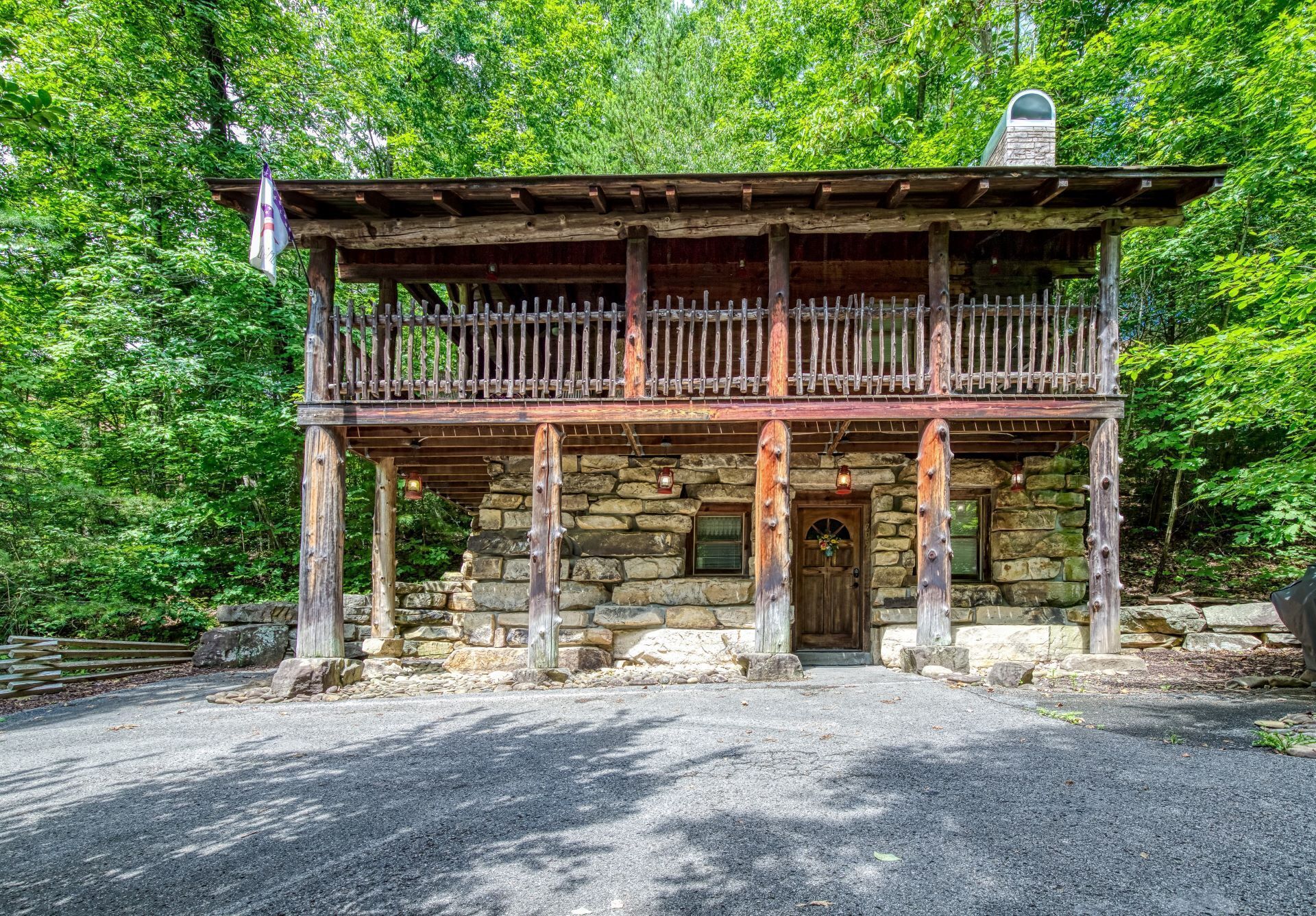 A rustic stone building with a wooden balcony and a stone chimney.