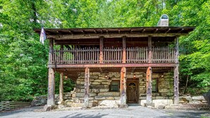 A rustic stone building with a wooden balcony and a stone chimney. - ER69 - Rachel's Tree House - Great location. Close to all the action! (Pigeon Forge)