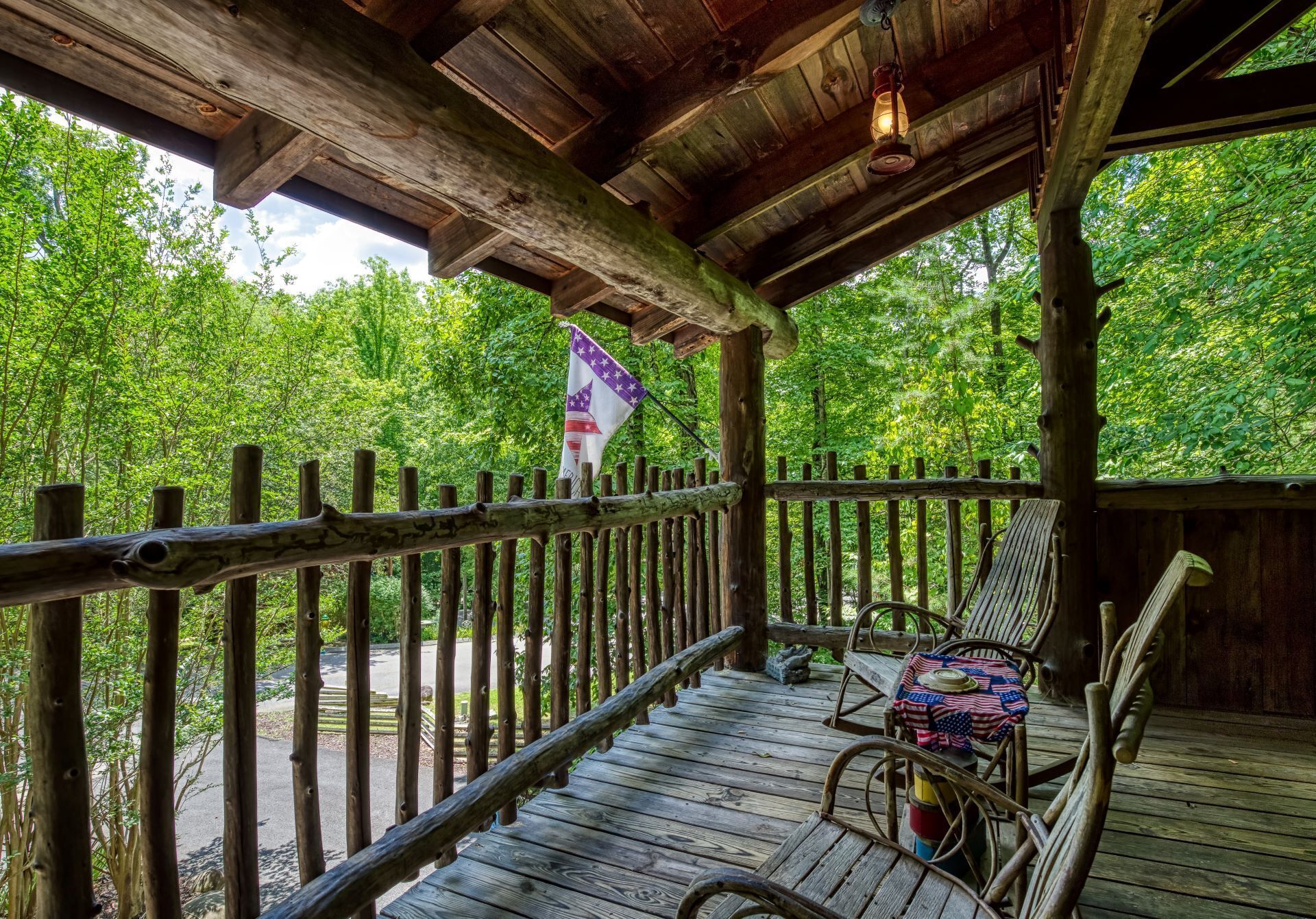 A wooden deck with a rustic railing, a flag, and two wicker chairs.