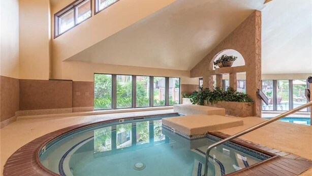 Ein Hallenbad mit einer gefliesten Kante, einem Holzboden und einer Steinwand.
