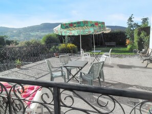 Een terras met tuinmeubilair, een patroonrijke parasol en uitzicht op het landschap.