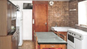 Een kleine keuken met een houten tafel, een gootsteen, een fornuis en kastjes.