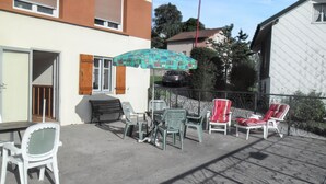 Een terras met tuinmeubilair, een tafel en een patroon paraplu.