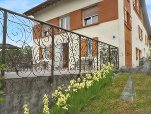A building with a balcony, a wrought iron railing, and yellow flowers in the foreground. - Homerez - Studio in Gérardmer (Gérardmer)