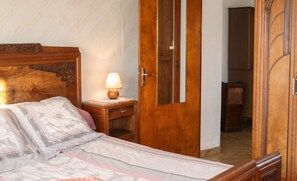 Een slaapkamer met een houten bed, een nachtkastje met een lamp en een kledingkast.
