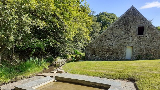 A stone building with a triangular roof, a small window, and a door. - Large stone house with garden near the beach (Héauville)