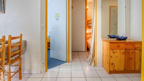 A room with a wooden dining table and chairs, a wooden cabinet with blue bowls, and a door leading to another room with a bunk bed. - T2 cabin 6 people in Luz, quiet, parking, pets allowed (Luz-Saint-Sauveur)