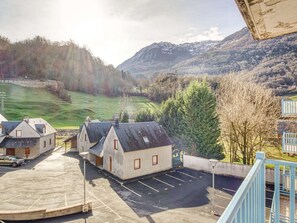 A parking area with several buildings, a mountain backdrop, and a clear sky.