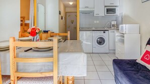 A compact living space with a dining area, a kitchen with a washing machine, and a sofa. - T2 cabin 6 people in Luz, quiet, parking, pets allowed (Luz-Saint-Sauveur)