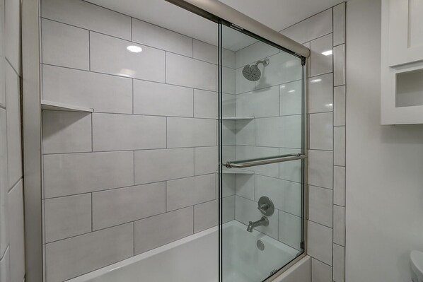 A glass-enclosed shower with white tiles, a glass door, and a metal handrail. - Beautiful condo at Channelview! Gated Communited, Private fishing pier, Large co (Port Aransas)