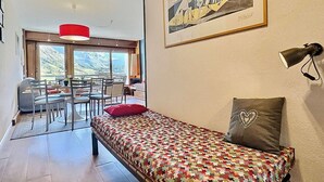A cozy room with a bed, a dining area, and a large window offering a mountain view. - Tignes, 6 pers, 55m², balcony, parking included (Tignes)