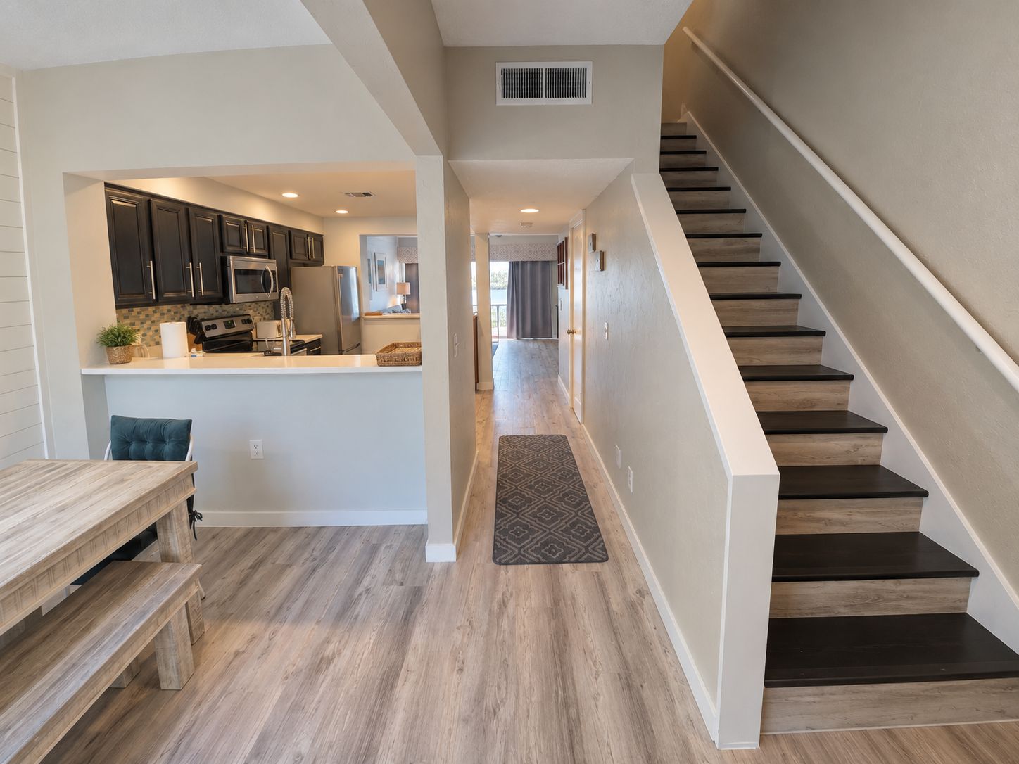 A modern kitchen with dark cabinets, a central island, and a dining area with a bench.
