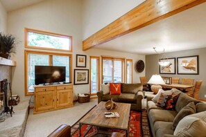 A spacious living room with a large TV, wooden beams, and a cozy seating area.