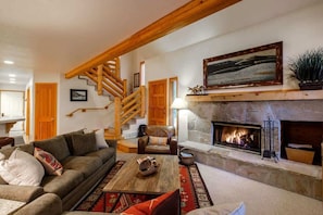 Una sala de estar acogedora con chimenea, una escalera y un sofá.