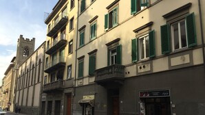Une vue de rue d’un immeuble doté d’une tour, de balcons et d’un restaurant appelé « Mala Gastronoma Pizzeria Paniniera ».