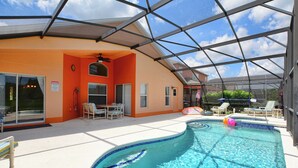 Una piscina con techo de vidrio, sillas de descanso y un área de patio techada.