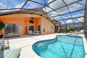 Una piscina techada con techo de vidrio, un área de patio con sillas y una pequeña mesa.