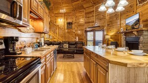 A log cabin interior with a kitchen, dining area, and living room. - Declan's View - Cozy 1 bedroom with Game room and Great Mountain Views! (Sevierville)