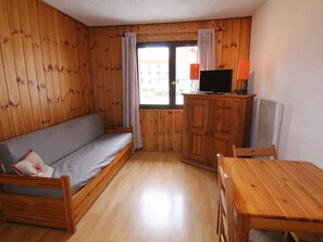 A wooden interior with a sofa, a table, and a cabinet.