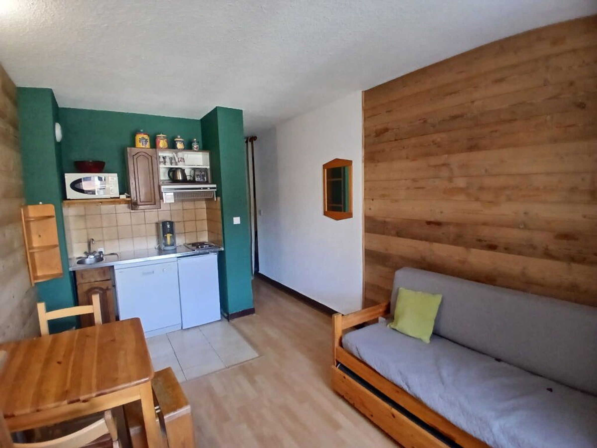 A compact living space with a kitchenette, a dining area, and a sofa.