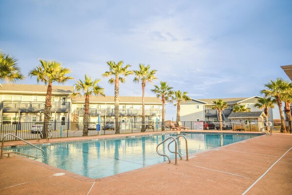 A swimming pool with palm trees and a building in the background.