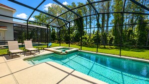 A swimming pool with a glass enclosure, lounge chairs, and a grassy area. - Private Pool & Spa | No Rear Neighbors | Walk to Clubhouse | 6BR Near Disney (Kissimmee)