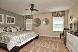 A bedroom with a bed, a ceiling fan, two wall decorations, and a dresser. - Private Pool & Spa | No Rear Neighbors | Walk to Clubhouse | 6BR Near Disney (Kissimmee)