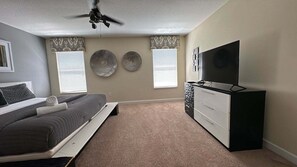 A bedroom with a bed, a dresser, a TV, and two decorative wall plates.