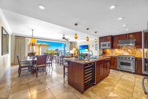 A spacious kitchen with a central island, modern appliances, and a view to the outside.
