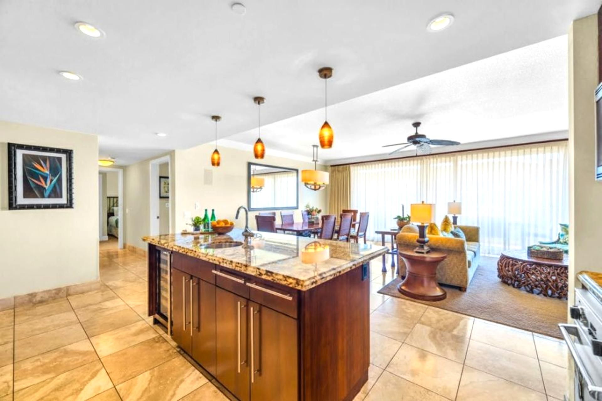 A spacious living area with a large kitchen island, dining table, and seating.