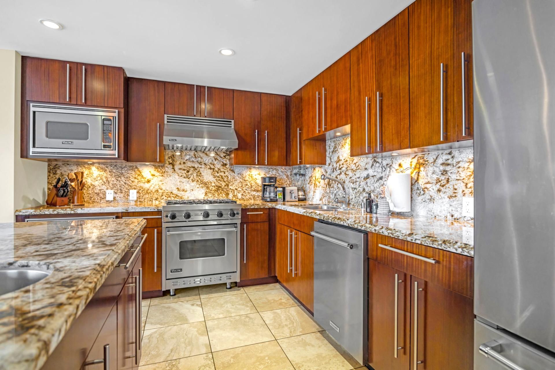 A modern kitchen with wooden cabinets, stainless steel appliances, and a granite countertop.