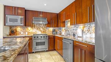 A modern kitchen with wooden cabinets, stainless steel appliances, and a granite countertop.