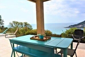Een terras met een tafel en stoelen, met uitzicht op de kust.
