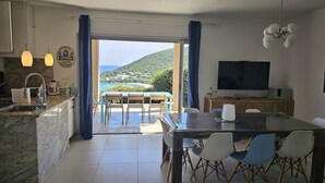Uma cozinha moderna com uma ilha grande, uma área de jantar com mesa e cadeiras, e uma televisão.