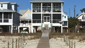 A beachfront property with a central building featuring multiple balconies and a covered walkway leading to the beach.
