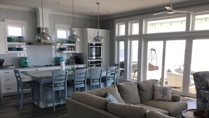 A modern kitchen with white cabinets, stainless steel appliances, and a dining area with blue chairs.