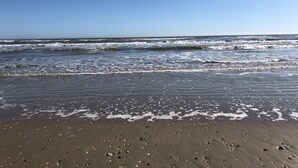 A beach with waves and footprints in the sand. - 2 Story Upscale Beachfront House With unobstructed Beach Views from every room. (Crystal Beach)