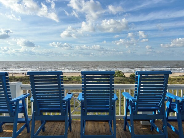 A deck with blue chairs facing the ocean.