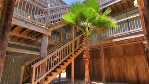Una escalera de madera que lleva a un balcón con una palmera.