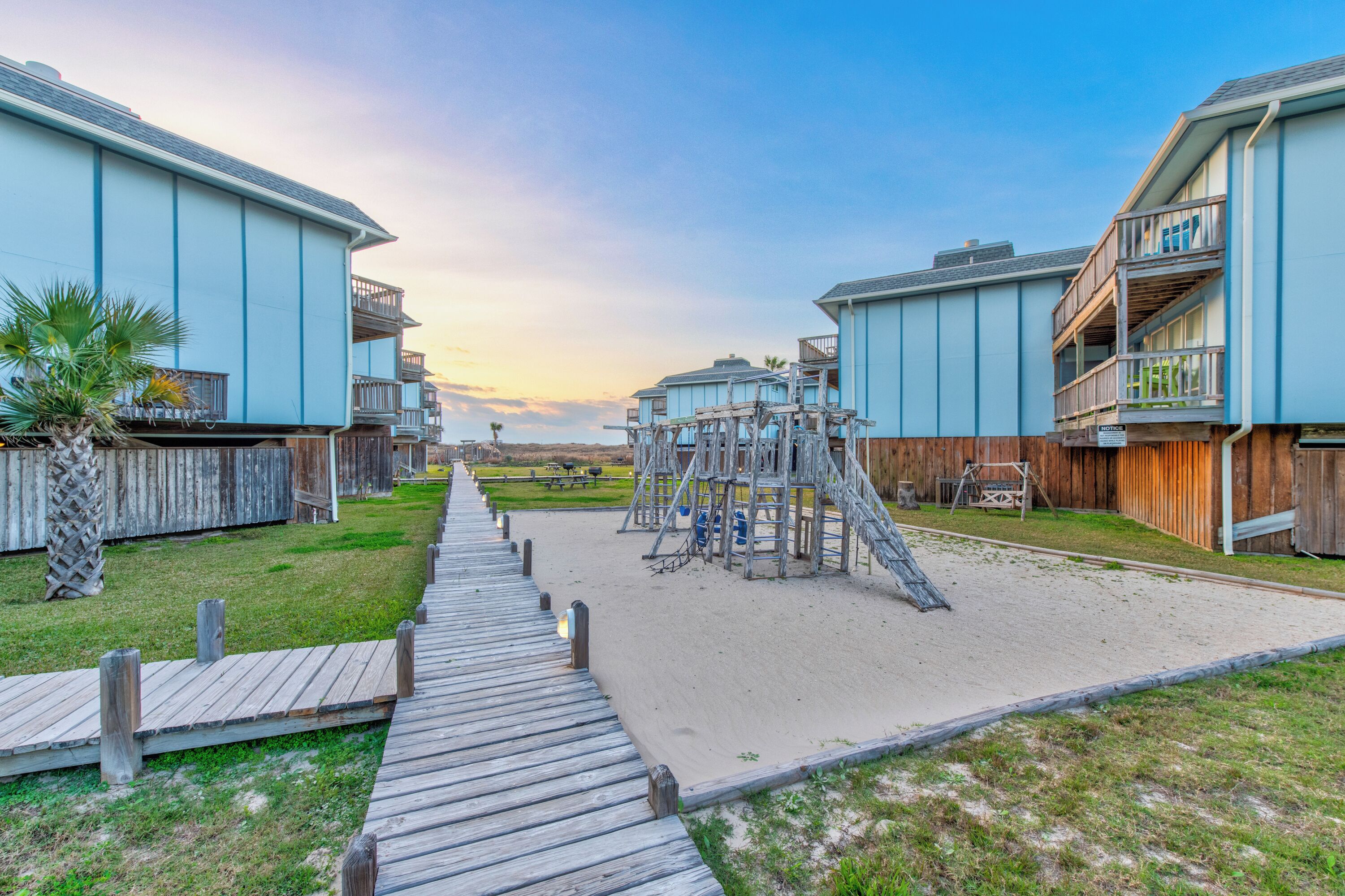 A beachfront property with wooden walkways, a playground, and beach houses.